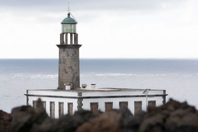 Lighthouse by sea against sky