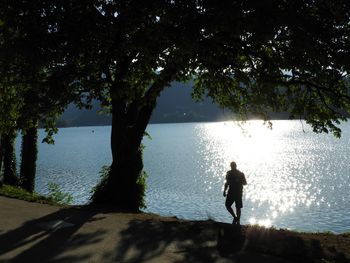 Silhouette man standing by sea against sky