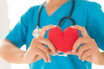 Midsection of doctor holding heart shape