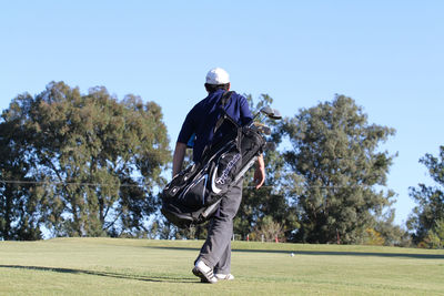 Rear view of person on golf course against sky