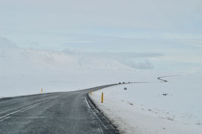 Road leading towards snowcapped mountains against sky