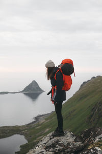 Rear view of man standing on mountain against sky