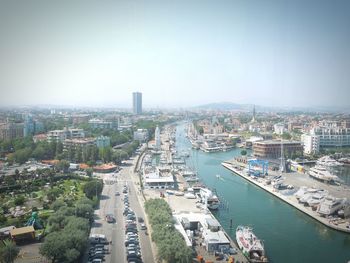 Aerial view of canal amidst buildings against clear sky on sunny day