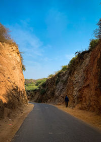 Rear view of man walking on road against sky