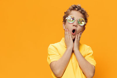 Portrait of young woman against yellow background