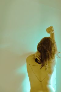 Rear view of woman standing against wall