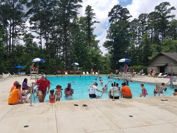 People sitting by swimming pool against sky