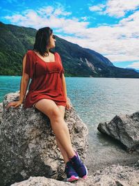 Woman on rock by mountains against sky