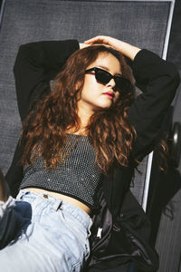 Young woman wearing sunglasses relaxing on chair at home