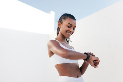 Young woman exercising against wall