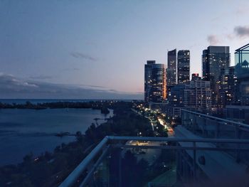 Illuminated buildings in city against sky at sunset