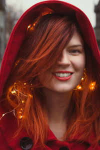 Close up smiling lady with red hood and fairy lights portrait picture
