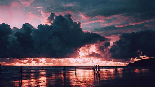 Silhouette people by sea against sky during sunset