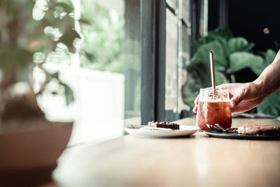 Close-up of hand holding drink on table in restaurant