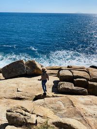 Full length of man standing on rock by sea against sky