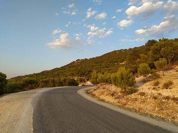 Empty road by mountains against sky