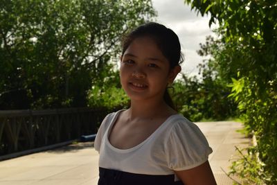 Portrait of smiling girl standing against trees