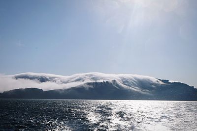 Scenic view of sea and snowcapped mountains against sky