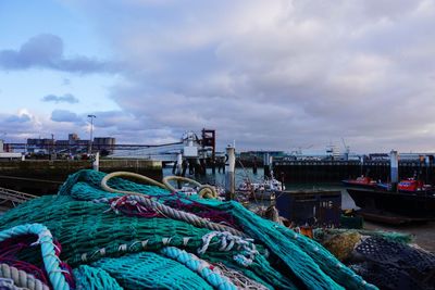 Boats moored at harbor against cloudy sky