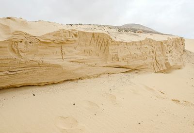 Carvings on rock covered with sand at beach