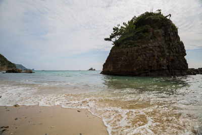 Rock formation on beach against sky