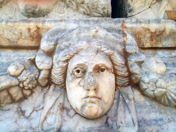 Close-up of old statue against wall