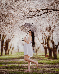 Full length of woman standing by tree