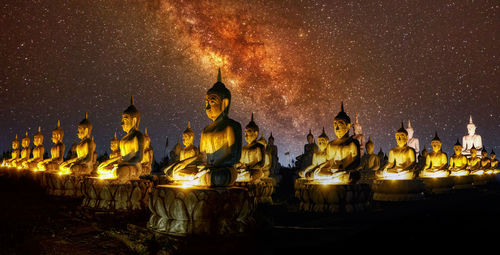 Panoramic view of statue by building against sky at night