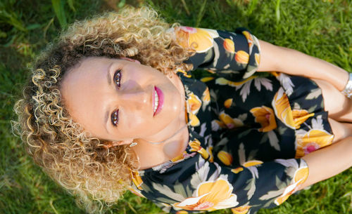 High angle portrait of smiling woman sitting on grass