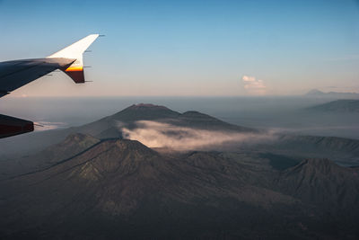 Airplane flying over snowcapped mountains against sky during sunset