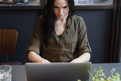 High angle view of serious businesswoman using laptop while sitting at table