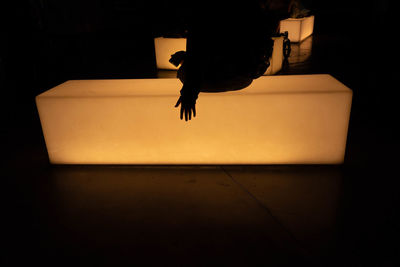 Rear view of silhouette woman jumping on the dark