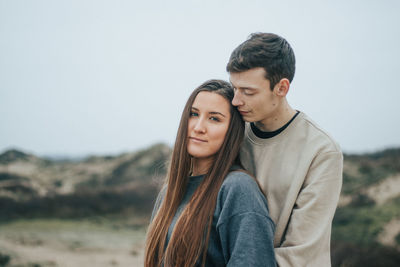 Portrait of young couple standing against sky