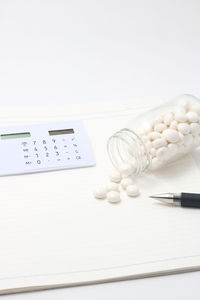 High angle view of calculator with medicines and book on table