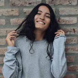 Portrait of smiling young woman standing against wall