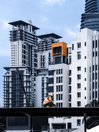Low angle view of a construction worker on a roof against apartment building in  the city
