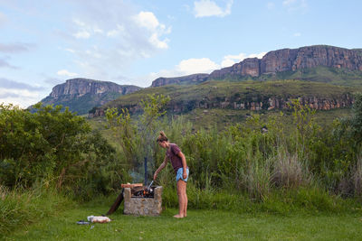 A woman is barbecuing with a view of drakensberg in the background