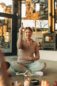 Woman with hand on stomach holding burning sandalwood sitting at retreat center