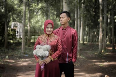 Young couple standing against trees