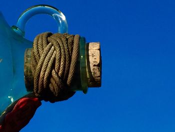 Low angle view of cropped woman holding hands against clear blue sky