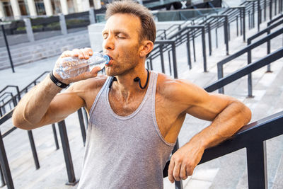 Man drinking water from while sitting outdoors