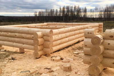 Stack of logs on field against sky