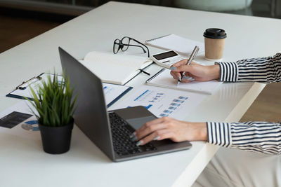 Midsection of businesswoman using laptop on table