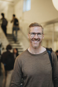 Portrait of happy mature male professor standing in university