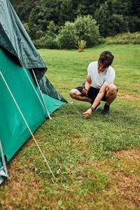 Young man putting up a tent on camping during summer vacation trip. teenager putting the stakes