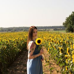 Woman holding sunflower while standing on land
