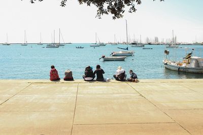 People sitting on sea against sky