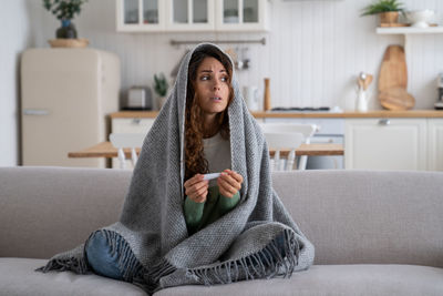 Young woman sitting on sofa at home