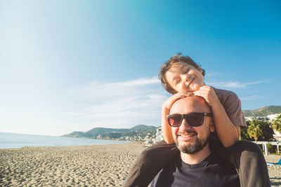 Boy sits on his father's shoulders