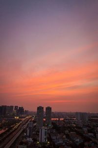 Illuminated cityscape against sky at sunset